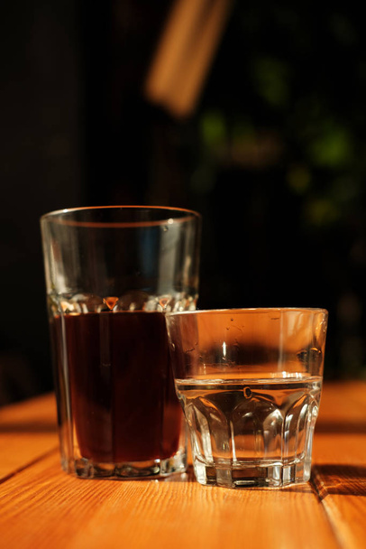 glasses of fresh cold brewed black coffee and clear water on cafe table - Foto, Imagem