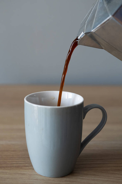 Koffie wordt gegoten in een mok uit een koffiepot - Foto, afbeelding