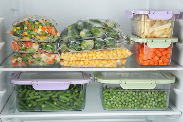 Plastic bags and containers with different frozen vegetables in refrigerator - Valokuva, kuva