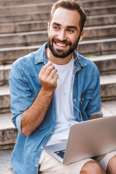 Handsome smiling young man using laptop computer - Φωτογραφία, εικόνα