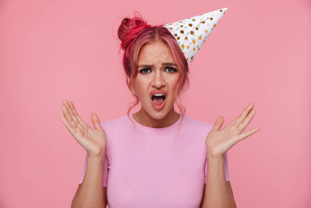 Portrait of young woman wearing party cone screaming and raising - Foto, Imagem