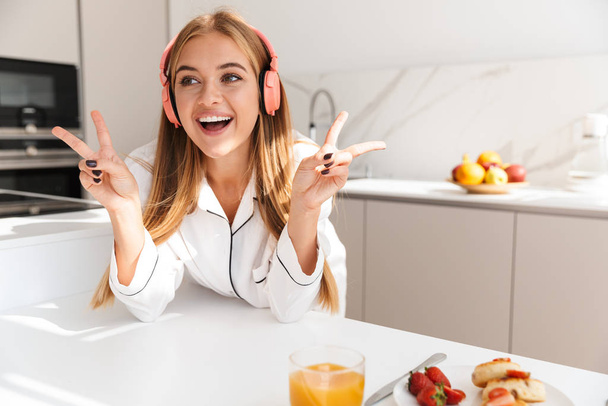 Photo of cheerful woman having breakfast and gesturing peace sign - Photo, image