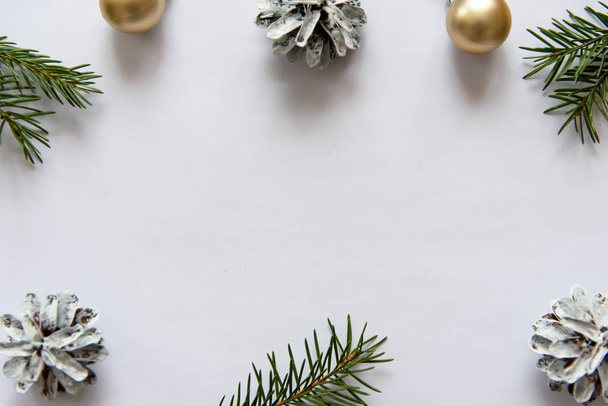 Joulu, koristelu valkoisella pöydällä tausta tyhjä valkoinen arkki. Uuden vuoden männynkäpyjä ja kultaisia joulupalloja. Tekstipaikka
. - Valokuva, kuva