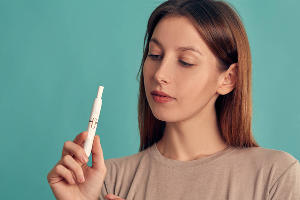 Electronic Cigarette Technology. Tobacco IQOS system. Close-up of a girl smoking an electric hybrid cigarette with a heating pad. tobacco heating system. - Photo, Image