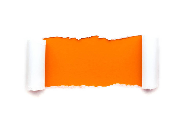 Un trou dans le papier blanc avec des bords déchirés isolés sur un fond blanc avec un fond de papier de couleur orange vif à l'intérieur
. - Photo, image
