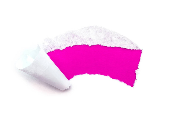 A hole in white paper with torn edges isolated on a white background with a bright pink color paper background inside. - Foto, Imagem
