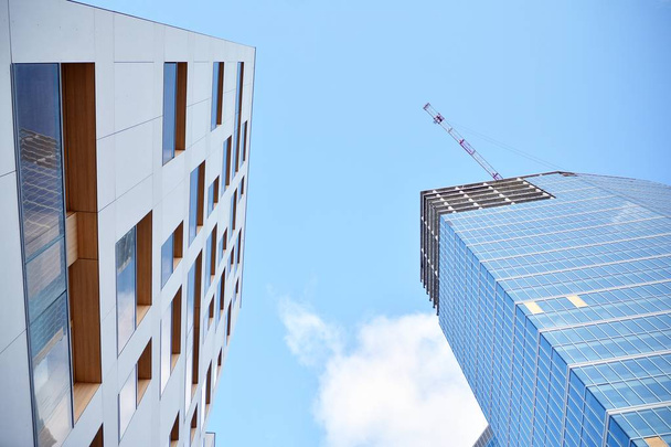 Novo arranha-céus de escritório moderno sendo construído em uma cidade. Edifício de fachada arquitetônica durante a construção com elementos de vidro acabados e em concreto
. - Foto, Imagem