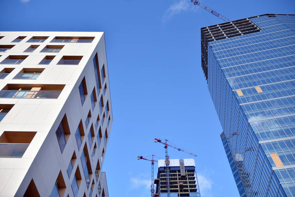 Novo arranha-céus de escritório moderno sendo construído em uma cidade. Edifício de fachada arquitetônica durante a construção com elementos de vidro acabados e em concreto
. - Foto, Imagem