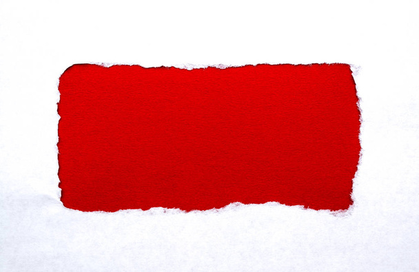 A hole in white paper with torn edges with a bright red color paper background inside. Good paper texture. - Zdjęcie, obraz