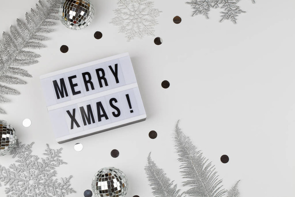 Hyvää joulua sanat valolaatikossa valkoinen lumihiutaleet, pallot, hopea puu oksat valkoisella pohjalla
 - Valokuva, kuva