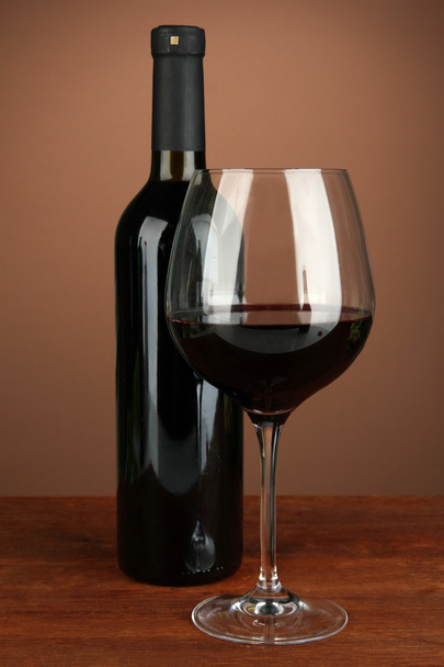 Composition of wine bottle and glass of red wine, on color background - Foto, Bild
