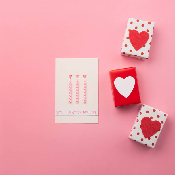 Scatole regalo confezionate a mano, cuori rossi e candele sul retro rosa
 - Foto, immagini