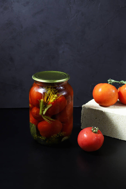 Zachowane i sfermentowane pomidory organiczne w szklanym słoiku na ciemnym tle. Koncepcja jedzenia w puszkach. Ochrona zbiorów rolnych. Warzywa konserwowane  - Zdjęcie, obraz