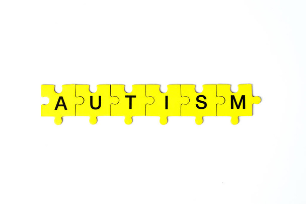 autism, concept the word autism is made up of puzzles in yellow with black letters - Foto, Imagen