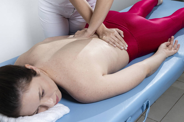 Terapeuta robi masaż pleców sportowcom w klinice. - Zdjęcie, obraz