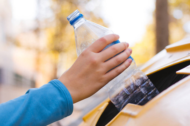Zdjęcie ręki kobiety poddającej recyklingowi plastikową butelkę - Zdjęcie, obraz
