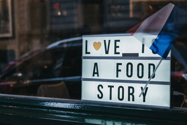 Φωτισμένο σήμα "Η αγάπη είναι μια ιστορία τροφίμων" με γαλλική σημαία resti - Φωτογραφία, εικόνα