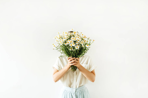 Jovem mulher bonita segurar em mãos buquê de flores margarida camomila branca no fundo branco
. - Foto, Imagem
