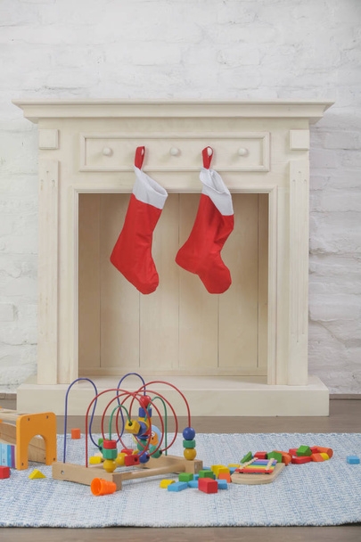 Deux chaussettes de Noël rouges suspendues à une cheminée en bois, concept de cadeau vacances d'hiver
 - Photo, image