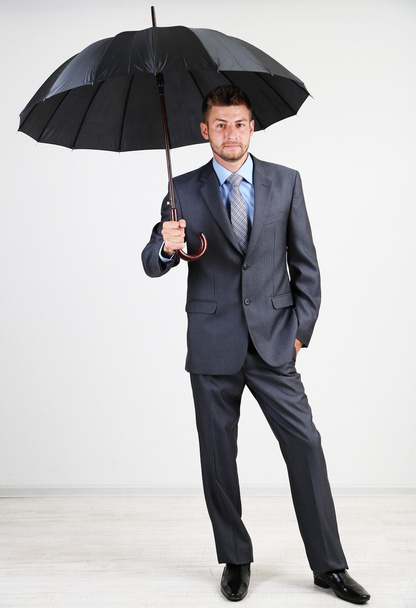 Businessman with umbrella. on gray background - Фото, изображение