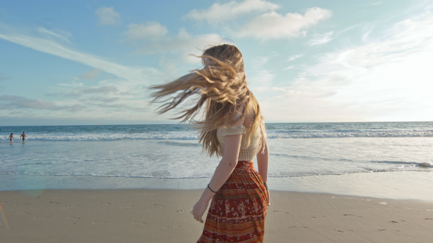 Krásná mladá žena kráčí na pláži a usmívá se na kameru - Záběry, video