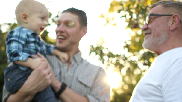 Close port, three generations of men of the same family in the park at sunset. Sun glare, happy family, fathers day - Footage, Video