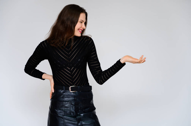 Concept adult girl on a white background. A photo of a pretty brunette girl in a black skirt and black sweater smiles and shows different emotions in different poses right in front of the camera. - 写真・画像