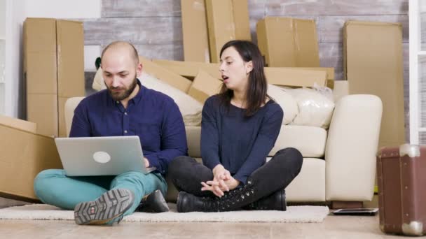 Casal sorrindo enquanto sentado no chão de seu novo apartamento
 - Filmagem, Vídeo