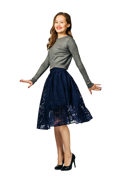 young beautiful woman in dark blue skirt and gray jumper smiles and rotating. isolated on white background - Φωτογραφία, εικόνα