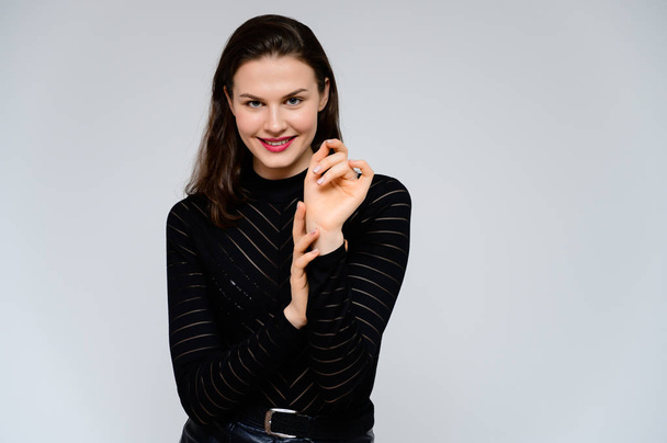 Concept adult girl on a white background. Large photo of a pretty brunette girl in a black sweater smiling and showing different emotions in different poses right in front of the camera. - Zdjęcie, obraz