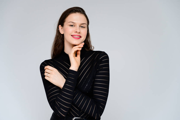 Concept adult girl on a white background. Large photo of a pretty brunette girl in a black sweater smiling and showing different emotions in different poses right in front of the camera. - Fotoğraf, Görsel