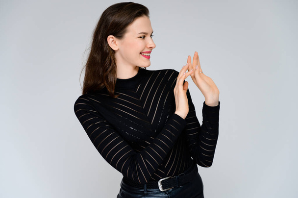 Concept adult girl on a white background. Large photo of a pretty brunette girl in a black sweater smiling and showing different emotions in different poses right in front of the camera. - Fotografie, Obrázek