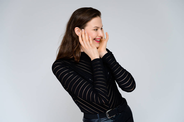 Concept adult girl on a white background. Large photo of a pretty brunette girl in a black sweater smiling and showing different emotions in different poses right in front of the camera. - Foto, Imagem