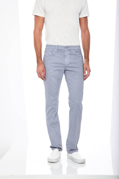 Nenáročné modré džíny spárované s bílou ležérní tričko a bílé mokasíny s bílým pozadím, Základní formální kalhoty pro pánské kalhoty spárované s černými příležitostnými tenisky a bílým pozadím - Fotografie, Obrázek