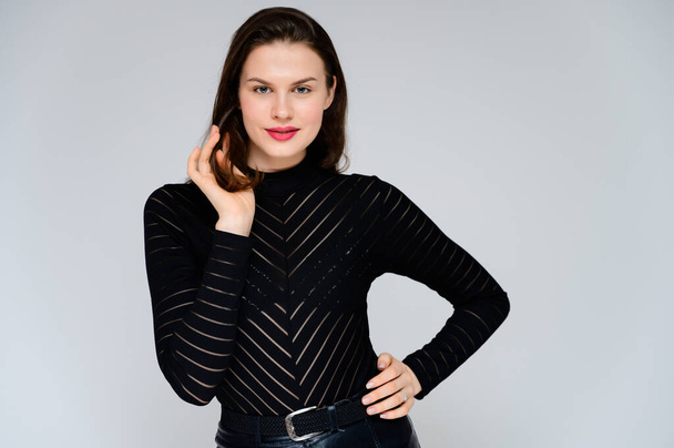 Concept adult girl on a white background. Large photo of a pretty brunette girl in a black sweater smiling and showing different emotions in different poses right in front of the camera. - Foto, imagen