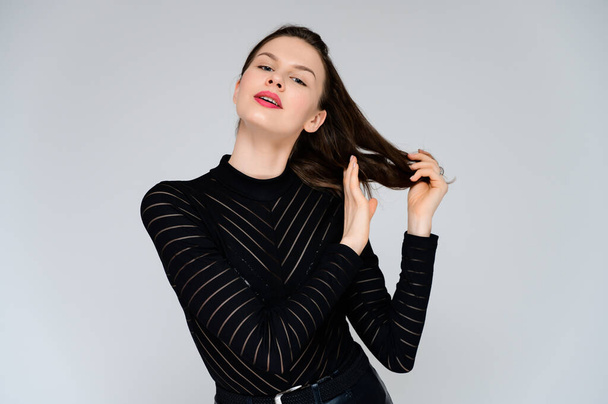 Concept adult girl on a white background. Large photo of a pretty brunette girl in a black sweater smiling and showing different emotions in different poses right in front of the camera. - Foto, immagini