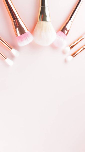 Makeup brushes on pink background. Set of golden makeup brushes, concept. Woman beauty accessory in pastel colors. Copy space. Widescreen - Zdjęcie, obraz