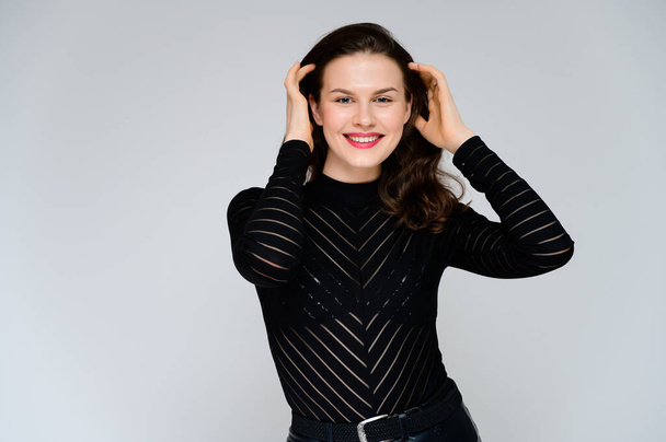 Concept adult girl on a white background. Large photo of a pretty brunette girl in a black sweater smiling and showing different emotions in different poses right in front of the camera. - Fotó, kép