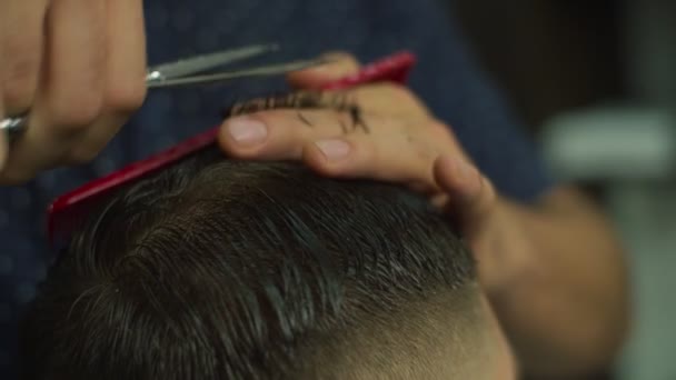 Close up of mans hair cutting by barbers scissors and comb in slow motion. Mans hands making male haircut in salon.  - Filmmaterial, Video