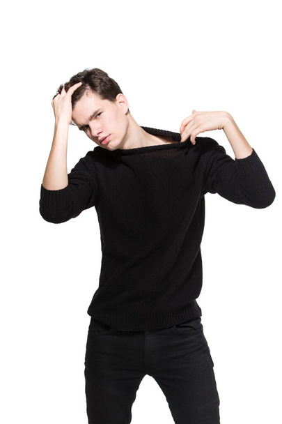 Siyah elbiseli genç erkek model stüdyo beyaz arka planda poz veriyor. Süslü kazak ve kot pantolon giyen beyaz adam izole edilmiş. Model genç beyaz adam. - Fotoğraf, Görsel