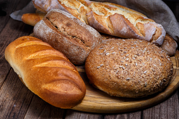 Assortment of baked bread on wooden table background - Foto, Bild