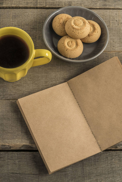 blank notebook, coffee and cookies on a wooden table - Photo, image