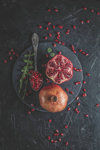 Fresh juicy pomegranate - whole and cut on a black vintage backg - Foto, Bild