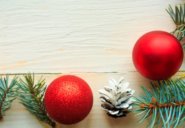 Rámeček větví vánočních stromků a červené ozdoby na bílém dřevěném pozadí. Vánoční přání. Mezera pro text - Fotografie, Obrázek