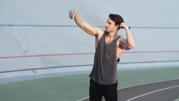 Sportovní muž protahování svaly pro selfie foto na moderní trati - Záběry, video