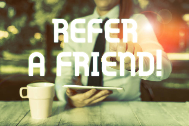 Text sign showing Refer A Friend. Conceptual photo direct someone to another or send him something like gift Female business person sitting by table and holding mobile phone. - Photo, Image
