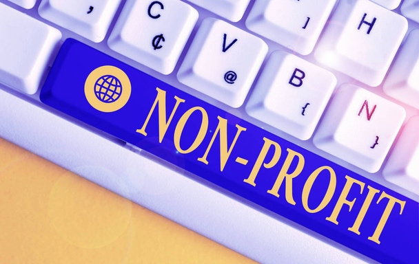 Text sign showing Non Profit. Conceptual photo type of organization that does not earn profits for its owners White pc keyboard with empty note paper above white background key copy space. - Photo, Image