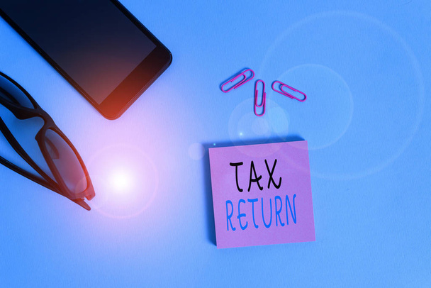 Conceptual hand writing showing Tax Return. Business photo showcasing which taxpayer makes annual statement of income circumstances Eyeglasses colored sticky note smartphone pastel background. - Photo, Image