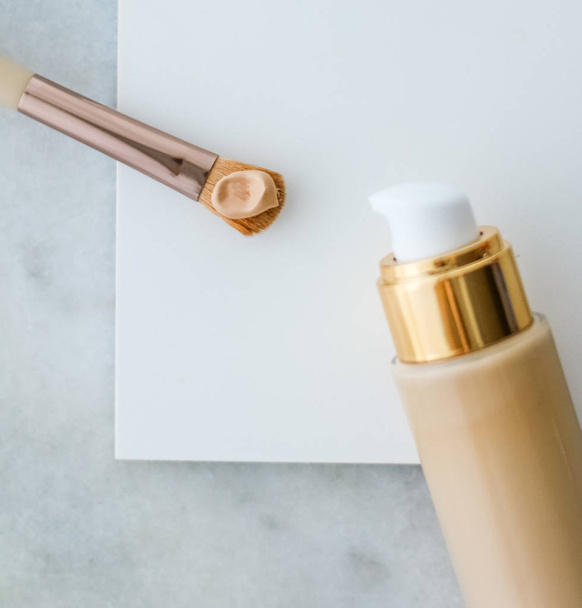 Makeup foundation bottle and contouring brush on marble, make-up - 写真・画像