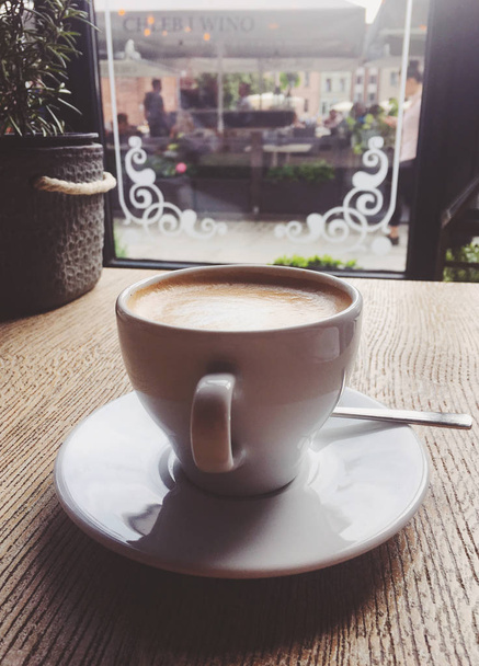 カフェテリアでホットカプチーノのカップ、木製のテーブルの上のコーヒーi - 写真・画像